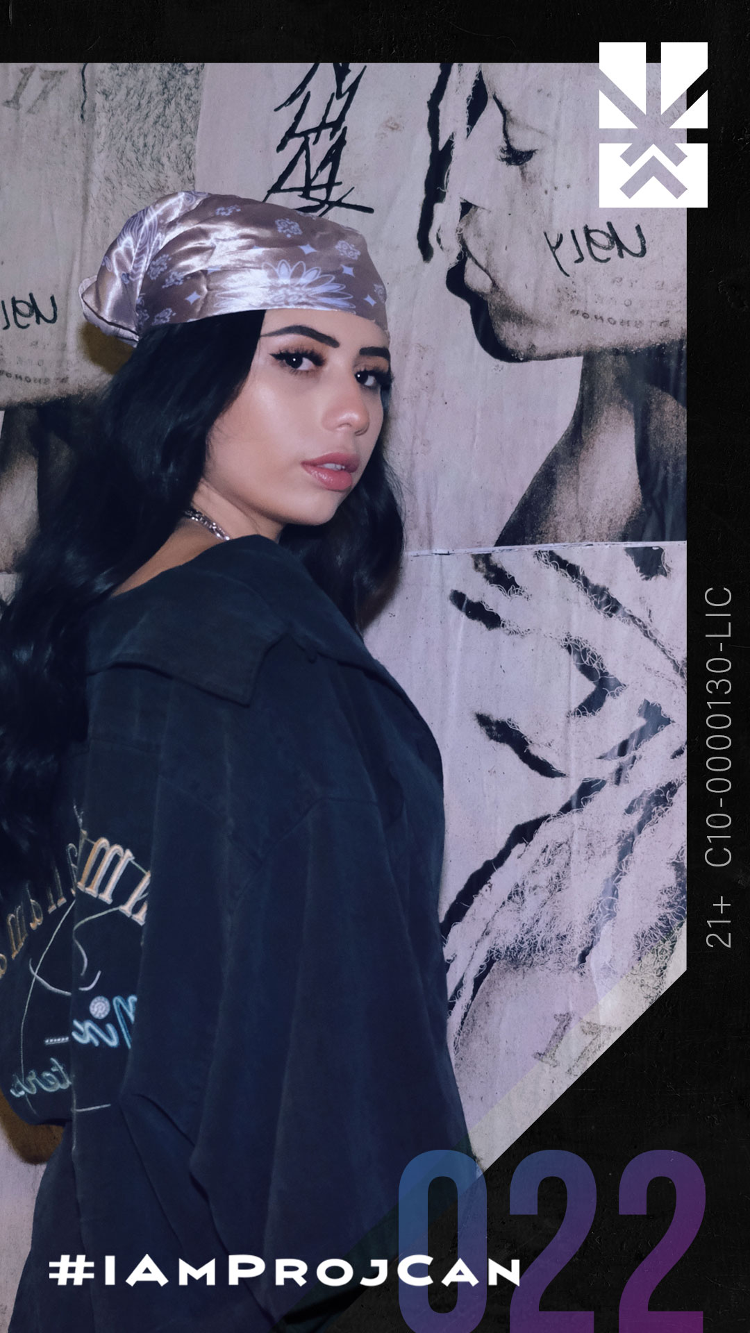 I’m ProjCan champion 022 posing in a black jacket and head scarf against an expressive art wall.
