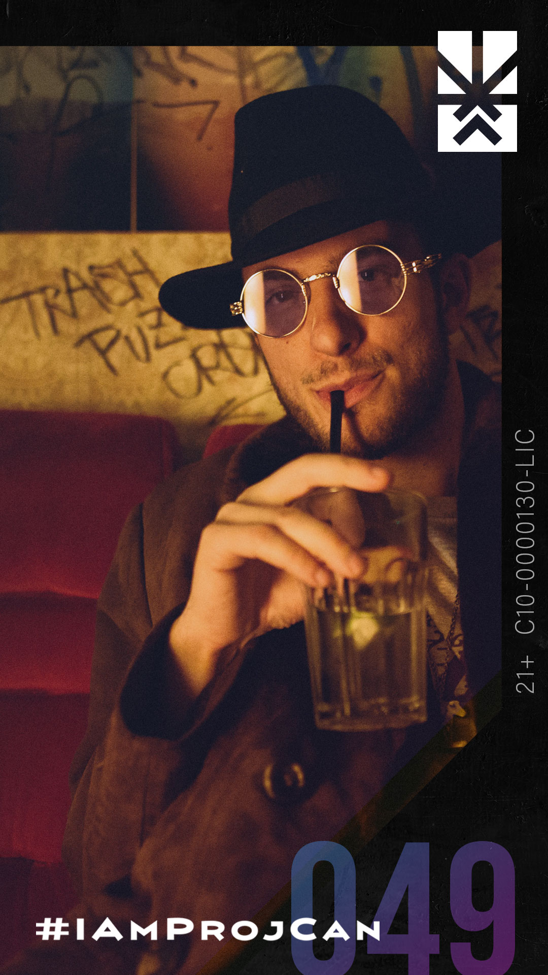 I’m ProjCan champion 049 wearing round glasses and a hat while holding a drink in a warmly lit setting.